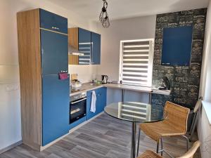 a kitchen with blue cabinets and a glass table at Pension Bernburg A2 in Bernburg