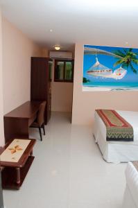 a bedroom with a bed and a desk and a painting at Grand Diamond Hotel Trinidad in Piarco