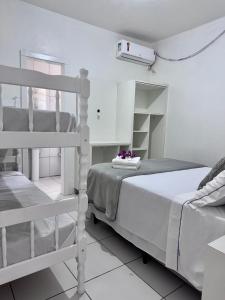 a white bedroom with a bunk bed and a shelf at Hotel Tropical in Torres