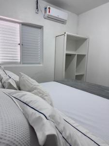 a white bed in a room with a window at Hotel Tropical in Torres