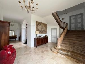 a large hallway with a staircase and a chandelier at Château de Mauhic - 15th century in Loubédat