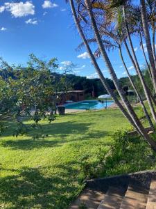 a view of a yard with a pool and palm trees at Chalés Vale Encantado - Serra do Cipó in Jaboticatubas +25 photos