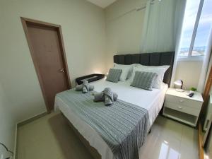 a bedroom with a bed with two stuffed animals on it at Praia da Graciosa Apartamento 2 quartos in Palmas