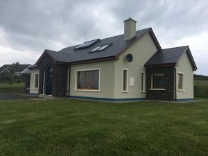 a house with a black roof on a grass field at Skellig Sanctuary in Dingle