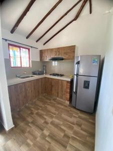 a kitchen with wooden cabinets and a stainless steel refrigerator at Hotel Arcoiris Mesa de los Santos in Los Santos