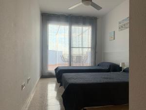 a room with three beds and a window at Casa Pera Ático duplex 1ª in Chilches