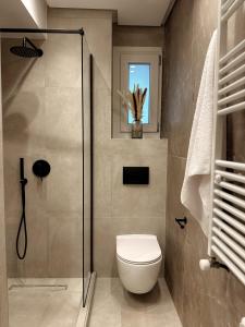 a bathroom with a toilet and a glass shower at AuRa The Golden Suite in Alexandroupoli