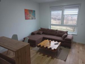 a living room with a brown couch and a table at Apartman Symbol in Tuzla