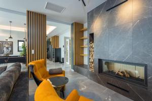 a living room with a fireplace and yellow chairs at Villa Titanium in Opatija