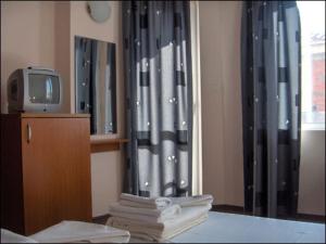a room with a tv and a curtain and towels at Sargas Sozopol in Sozopol +11 photos