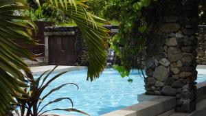 a swimming pool with a wooden door next to a stone wall at MOOREA - Waterfall Pool Coconut House 1 in Pihaena