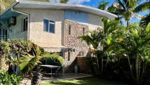 a house with palm trees in front of it at MOOREA - Waterfall Pool Coconut House 1 in Pihaena