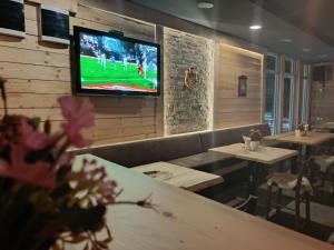 a restaurant with tables and a television on a wall at Etno kuca Brzece in Brzeće