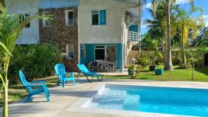 a patio with blue chairs and a swimming pool at MOOREA - Coconut Pool House 4 in Pihaena
