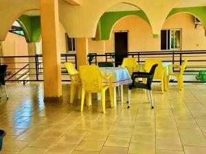 a dining room with yellow chairs and a table at appartment émeraude in Kribi