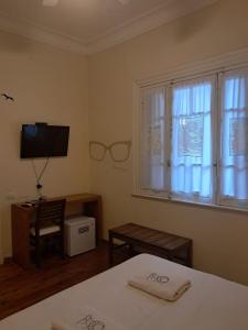 a bedroom with a bed and a tv and a window at Le Vrero Boutique Hotel in Colonia del Sacramento