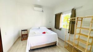 a bedroom with a bed with white sheets and a window at Quitinetes espaçosos com ar para um casal na Ilha de Boipeba in Ilha de Boipeba