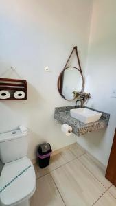 a bathroom with a white toilet and a sink at Quitinetes espaçosos com ar para um casal na Ilha de Boipeba in Ilha de Boipeba