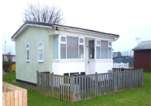 a small house with a fence in a yard at Chalet 147 South Shore Bridlington in Bessingby