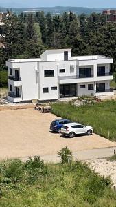 two cars parked in a parking lot in front of a house at Morea Apartments in Ulcinj