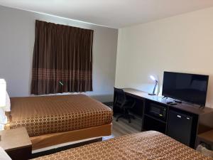 a hotel room with two beds and a desk with a television at Regency Inn & Suites in Milton