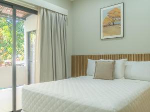 a bedroom with a large white bed and a window at Miradora House in El Sunzal