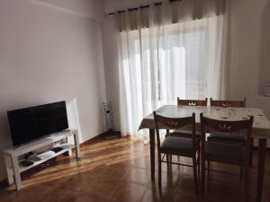 a dining room with a table and chairs and a television at Blue Apartment in Portimão