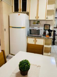 a kitchen with a white refrigerator and a table at Casa Nina, com Piscina e Brinquedoteca, Super Próxima das Cataratas e Aeroporto in Foz do Iguaçu