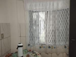 a window with a white curtain in a bathroom at Espaço Ideal 6 in Cascavel