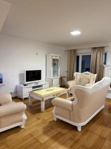 a living room with white furniture and a flat screen tv at Blumont aparthotel durres in Durrës