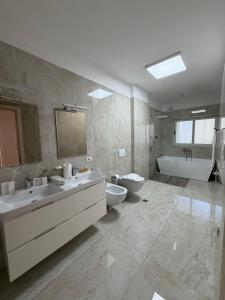 a bathroom with two sinks and a tub and a toilet at Blumont aparthotel durres in Durrës +93 photos