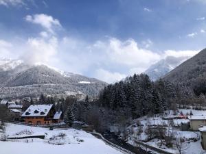 a village in the snow with mountains in the background at Appartamento Castellaccio in Ponte di Legno