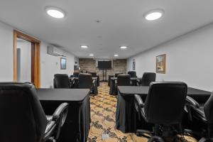 a conference room with tables and chairs and a screen at Hotel Manoir D'Auteuil - Par Aneyro in Quebec City
