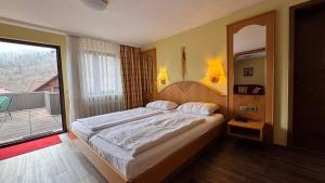 a bedroom with a large bed and a balcony at Hotel Restaurant Freihof in Oberharmersbach
