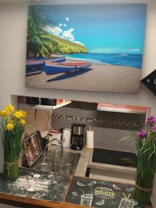 a kitchen with a sink and a picture of a beach at Charmant appart in Fort-de-France
