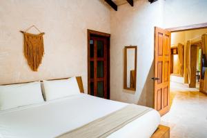 a bedroom with a white bed and an open door at Playa Cielo Beachfront Hotel - Santa Teresa, Costa Rica in Santa Teresa Beach