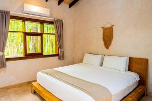 a bedroom with a large white bed and a window at Playa Cielo Beachfront Hotel - Santa Teresa, Costa Rica in Santa Teresa Beach