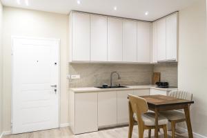 a kitchen with white cabinets and a wooden table at Luxury City View Apartments with Balcony & Kitchen & Fast Wi-Fi in Shkodër