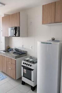 a kitchen with a white stove and a refrigerator at Ilha Aruba Condomínio na Cohama próx a praia in São Luís