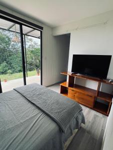a bedroom with a flat screen tv and a bed at Kèbi Container Home near Blue Falls in Colonia