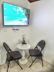 a table with two chairs and a tv on a wall at Nadiyah's Escape in Rock Sound