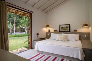 a bedroom with a bed and a large window at Casa Pini - Condomínio Altos de Trancoso, próxima ao Quadrado in Trancoso +78 photos