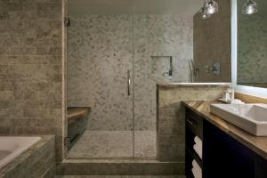a bathroom with a shower and a tub and a sink at Loews Chicago Hotel in Chicago