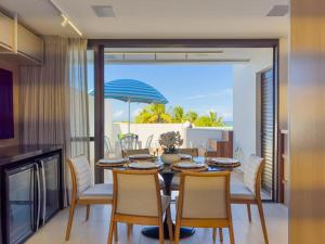 a dining room with a table and chairs and an umbrella at Duplex com Piscina Privativa em Itacimirim! in Camaçari