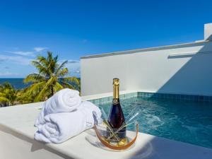 a bottle of champagne sitting on a ledge next to a swimming pool at Duplex com Piscina Privativa em Itacimirim! in Camaçari