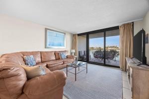 a living room with a brown leather couch and a television at Wind Drift North 214 2BD, 2BA in Orange Beach
