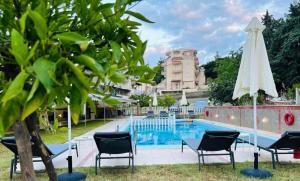 a pool with chairs and a table and a white umbrella at Apartments Spartacus in Polychrono