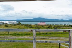 a fence with a view of the water and a boat at Kayenwuouk, Puerto Natales in Puerto Natales