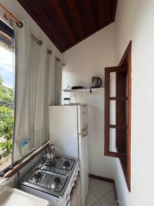 a kitchen with a stove and a white refrigerator at Bora Bora Geribá Kitnet in Búzios
