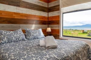 a bedroom with a bed with a large window at Kayenwuouk, Puerto Natales in Puerto Natales